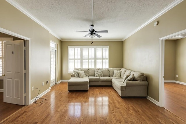 unfurnished living room with baseboards, light wood finished floors, ceiling fan, ornamental molding, and a textured ceiling