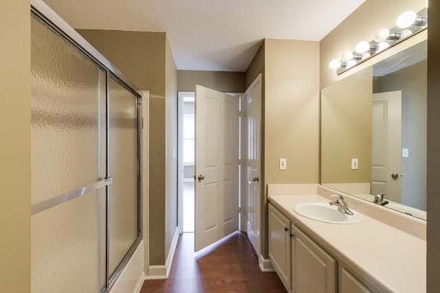 full bathroom featuring baseboards, wood finished floors, and vanity