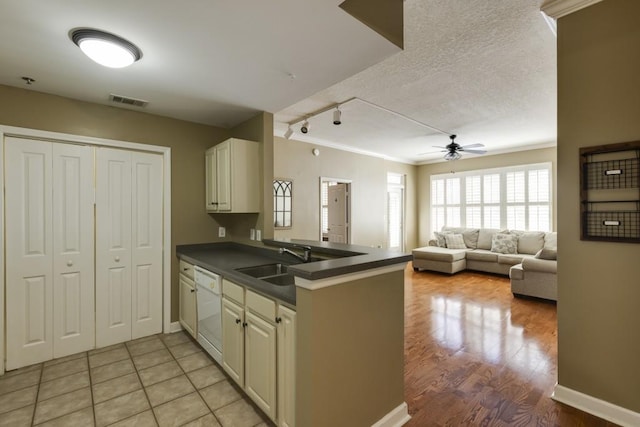 kitchen featuring dark countertops, visible vents, dishwasher, a textured ceiling, and a sink