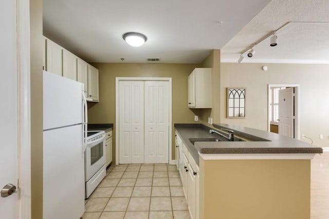 kitchen featuring white appliances, dark countertops, visible vents, and a sink