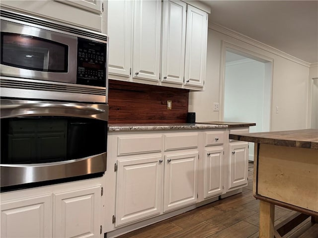 kitchen with appliances with stainless steel finishes, dark hardwood / wood-style floors, and white cabinets