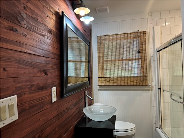 bathroom featuring sink, wood walls, and toilet