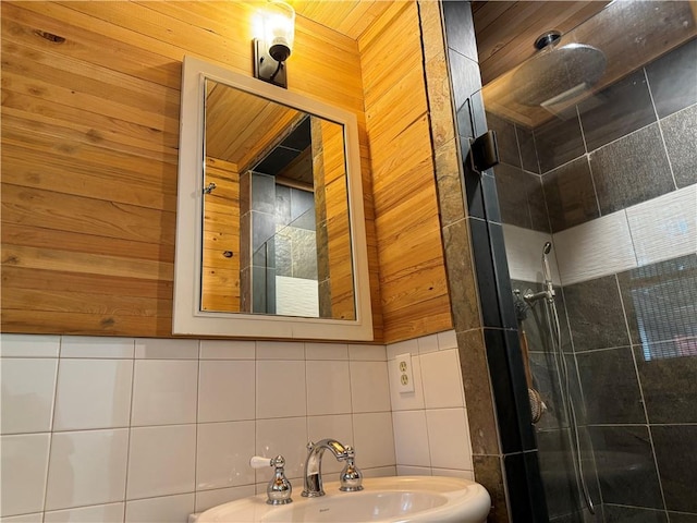 bathroom featuring decorative backsplash, tile walls, a shower with door, and sink