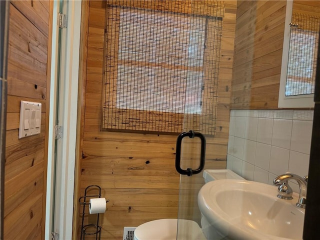 bathroom featuring wood walls, sink, and toilet