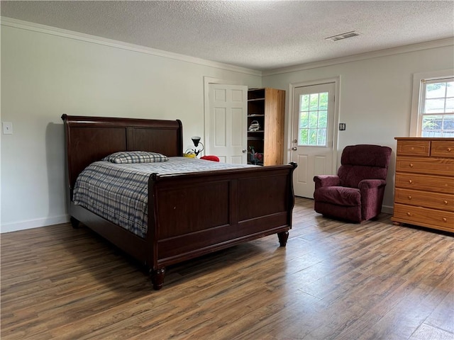 bedroom with dark hardwood / wood-style floors, ornamental molding, and a textured ceiling