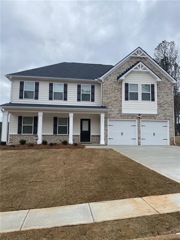 view of front of home with a garage, covered porch, brick siding, and driveway