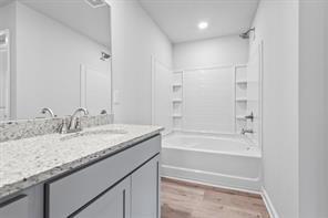 kitchen featuring appliances with stainless steel finishes, light stone counters, light wood-type flooring, a sink, and recessed lighting