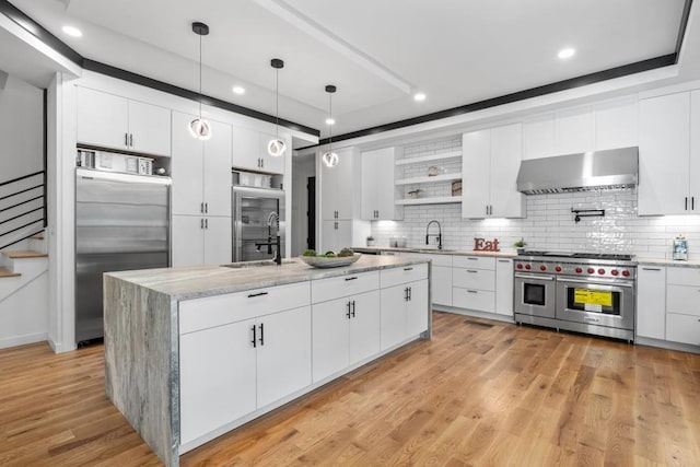 4366 Skyland Dr NE, Atlanta, GA 30342 - kitchen featuring wall chimney range hood, open shelves, high quality appliances, white cabinets, and backsplash