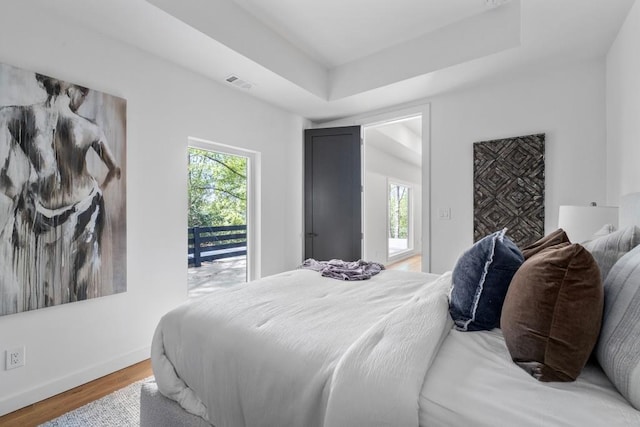 4366 Skyland Dr NE, Atlanta, GA 30342 - bedroom featuring baseboards, a tray ceiling, wood finished floors, and visible vents