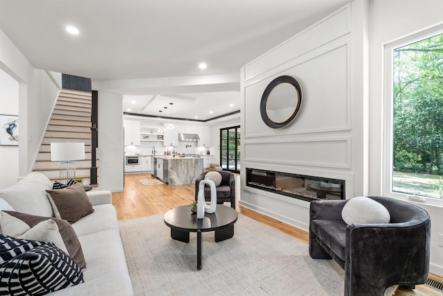 4366 Skyland Dr NE, Atlanta, GA 30342 - living room with light wood-style flooring, a glass covered fireplace, recessed lighting, and stairway