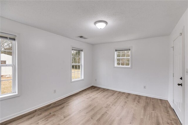 unfurnished room featuring a textured ceiling and light hardwood / wood-style floors