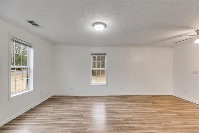 empty room with ceiling fan, ornamental molding, light hardwood / wood-style flooring, and a textured ceiling