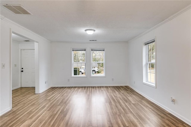 empty room featuring ornamental molding, plenty of natural light, and light hardwood / wood-style flooring