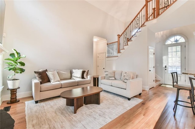 living room featuring a towering ceiling and light wood-type flooring