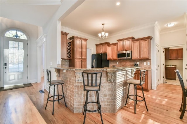 kitchen featuring black fridge, a breakfast bar area, light stone counters, and kitchen peninsula