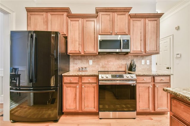 kitchen featuring crown molding, appliances with stainless steel finishes, light stone countertops, and tasteful backsplash