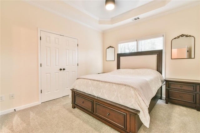 bedroom featuring light carpet, a closet, crown molding, and a raised ceiling