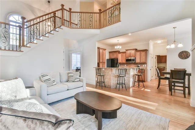 living room with crown molding, a healthy amount of sunlight, a notable chandelier, and light hardwood / wood-style floors