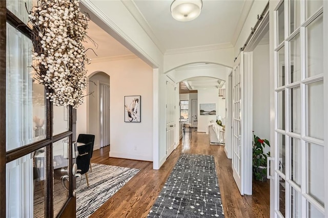 corridor featuring ornamental molding, arched walkways, french doors, and wood finished floors