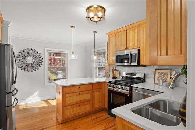 kitchen featuring kitchen peninsula, decorative light fixtures, stainless steel appliances, tasteful backsplash, and sink