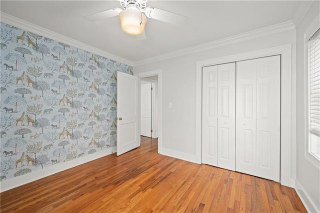 unfurnished bedroom featuring ceiling fan, hardwood / wood-style floors, a closet, and crown molding