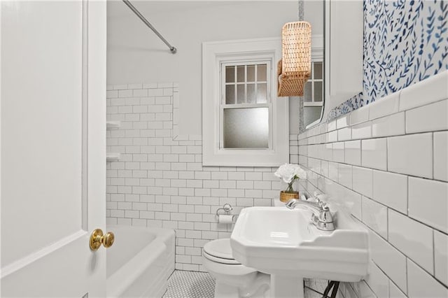 full bathroom with toilet, tile patterned flooring, washtub / shower combination, tile walls, and sink