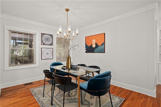 dining room with wood-type flooring, ornamental molding, and a chandelier