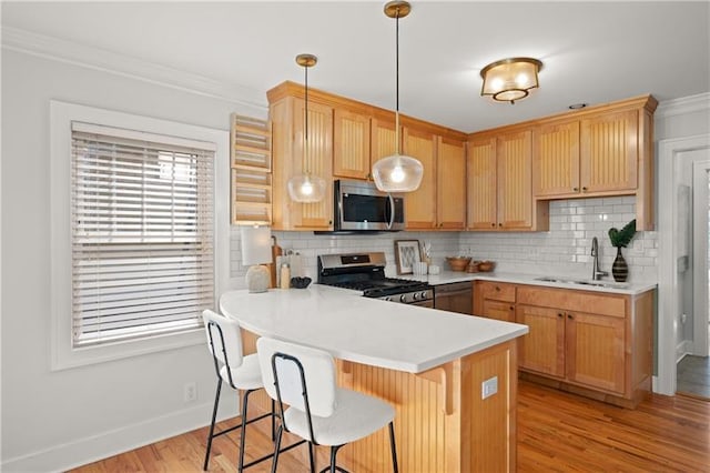 kitchen with stainless steel appliances, kitchen peninsula, pendant lighting, sink, and backsplash