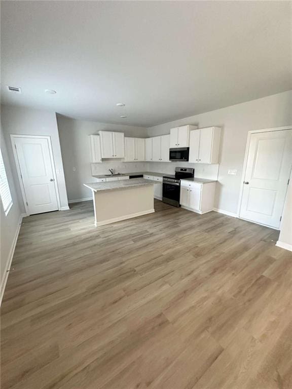 119 Deer Xing, Temple, GA 30179 - kitchen featuring electric stove, white cabinetry, light wood-type flooring, a center island, and light countertops