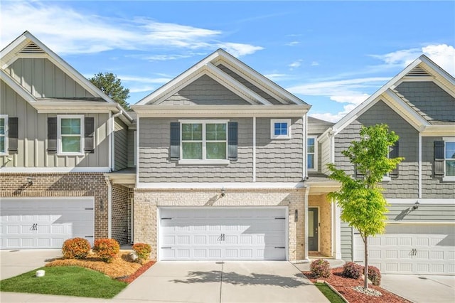 townhome / multi-family property featuring a garage, brick siding, board and batten siding, and driveway