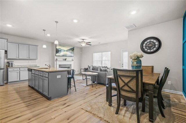 dining room featuring light wood finished floors, recessed lighting, a fireplace, ceiling fan, and visible vents