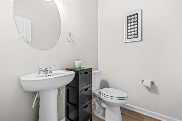 bathroom with toilet, wood finished floors, and baseboards