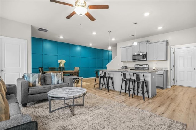 living area featuring ceiling fan, light wood-style floors, visible vents, and recessed lighting