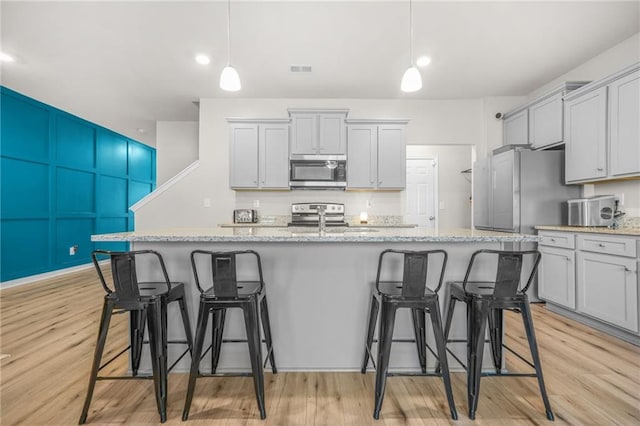 kitchen featuring a breakfast bar, light stone countertops, appliances with stainless steel finishes, and a sink