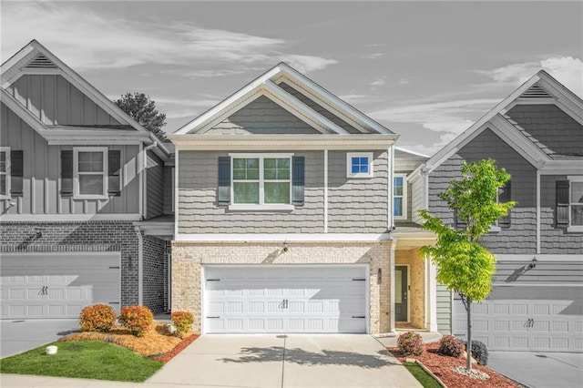 multi unit property with brick siding, board and batten siding, driveway, and an attached garage