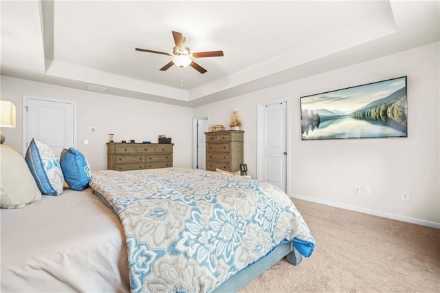 carpeted bedroom featuring a raised ceiling, a ceiling fan, visible vents, and baseboards