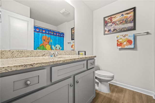 bathroom with wood finished floors, toilet, vanity, baseboards, and visible vents