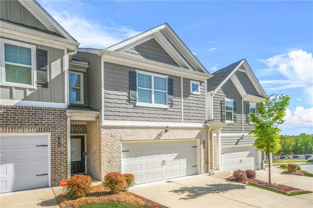 townhome / multi-family property with driveway, a garage, board and batten siding, and brick siding