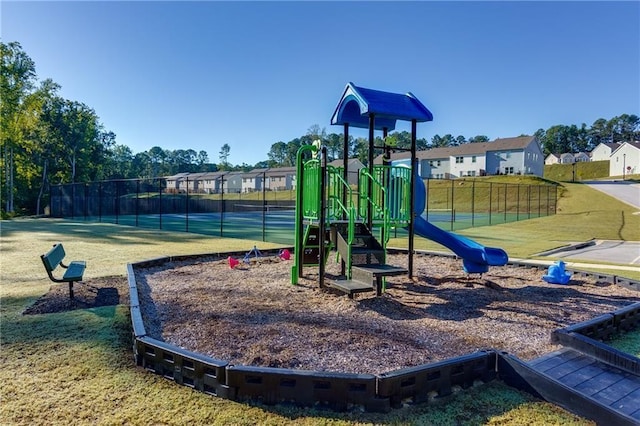 community jungle gym with a lawn and fence
