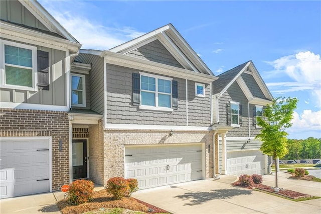 townhome / multi-family property featuring brick siding, board and batten siding, concrete driveway, and an attached garage