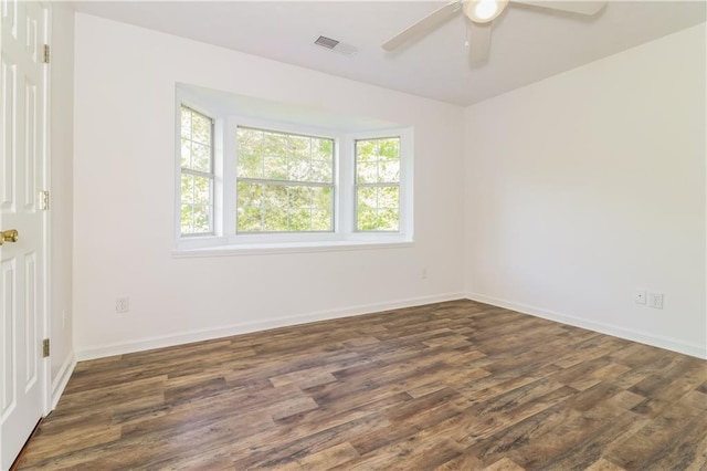 empty room featuring a ceiling fan, baseboards, dark wood-style floors, and visible vents