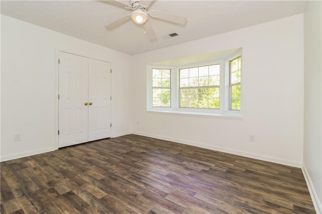unfurnished bedroom featuring dark wood-type flooring, a closet, a ceiling fan, visible vents, and baseboards