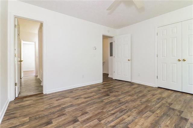 unfurnished bedroom with a closet, ceiling fan, baseboards, and dark wood finished floors