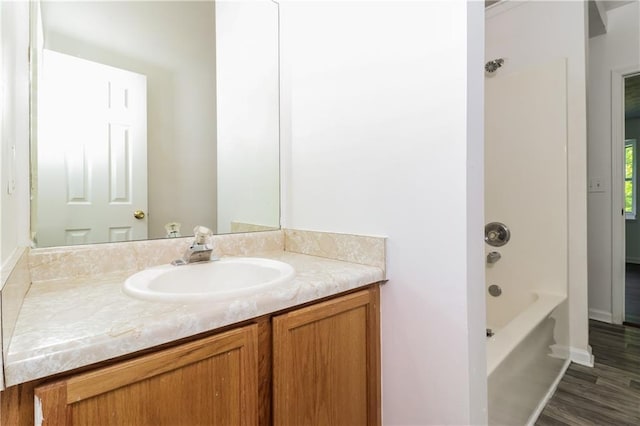 full bath featuring wood finished floors, vanity, baseboards, and shower / bathtub combination