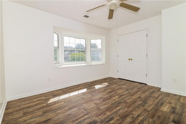 empty room featuring ceiling fan, baseboards, dark wood-style floors, and visible vents