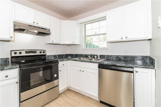 kitchen with white cabinets, a sink, appliances with stainless steel finishes, dark countertops, and under cabinet range hood