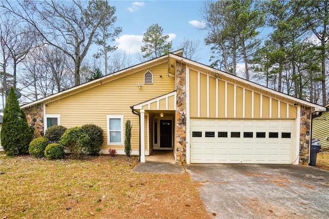 mid-century home featuring a garage, stone siding, board and batten siding, and concrete driveway