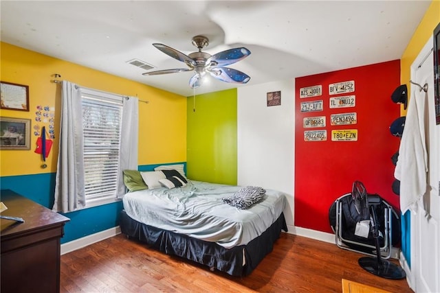 bedroom featuring baseboards, visible vents, ceiling fan, and wood finished floors