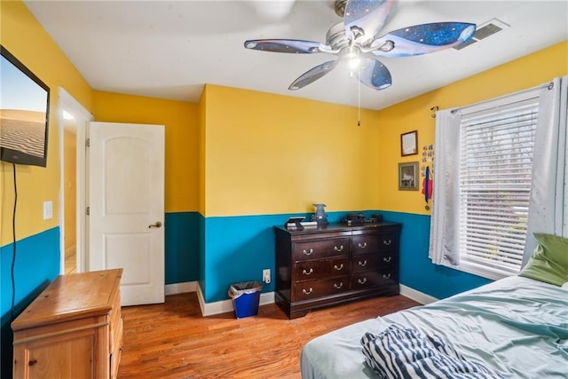 bedroom with multiple windows, baseboards, and wood finished floors