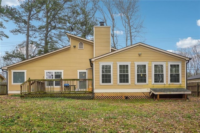 rear view of property with a yard, a chimney, a wooden deck, and fence